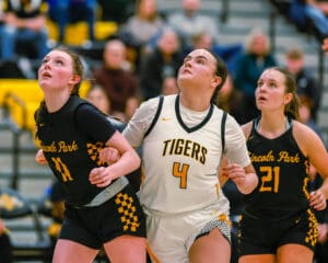 High school girls basketball game action, players in intense focus during a play.
