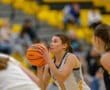 Focused female basketball player preparing to shoot during a game, with blurred spectators in the background.