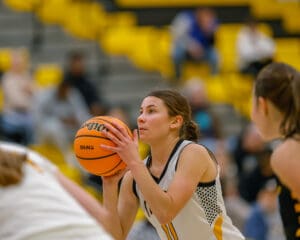 Focused female basketball player preparing to shoot during a game, with blurred spectators in the background.