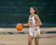 Female basketball player dribbles ball on court during game, wearing a Tigers jersey.