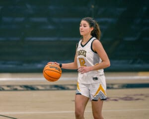 Female basketball player dribbles ball on court during game, wearing a Tigers jersey.