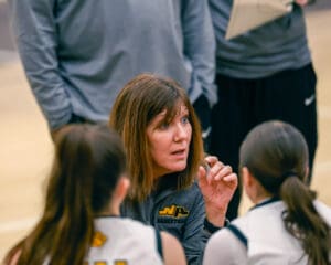 Basketball coach giving strategy advice to players during a timeout.