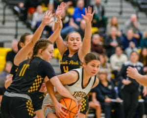 Girls' high school basketball game action with players competing for the ball on the court.