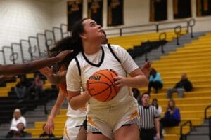 Female basketball player in white jersey focuses on scoring during an intense game.