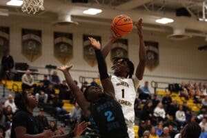 Basketball game: North Allegheny player shooting over Woody High opponent in a competitive match.