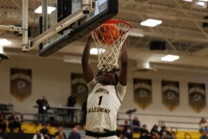 Basketball player from North Allegheny scores a slam dunk during a game in a gymnasium.