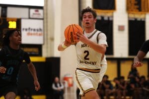 Basketball player from North Allegheny dribbling past a defender during a game in a gymnasium.