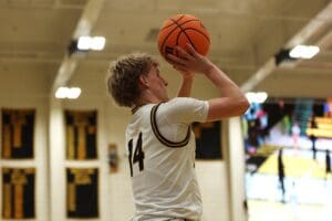 Basketball player in jersey number 14 shooting a basketball in an indoor court during a game.
