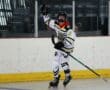 Young athlete celebrating a goal during a roller hockey game in an indoor rink.