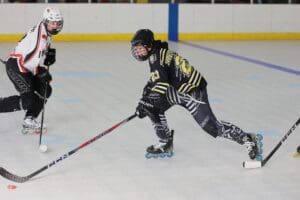 Roller hockey match action with players competing for the puck on the rink.