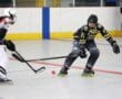 Two inline hockey players in action on the rink, competing for the puck.