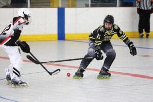 Two inline hockey players in action on the rink, competing for the puck.