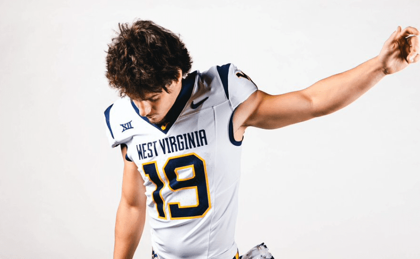 Football player in West Virginia jersey number 19 striking a pose against a plain background.