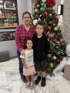 Family posing by a decorated Christmas tree indoors, holiday spirit with colorful ornaments.