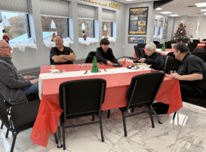 Group enjoying festive holiday gathering at a decorated table with Christmas themes and cheerful atmosphere.