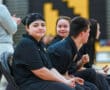 Young athletes sitting on a bench at a sports event, wearing matching black uniforms, with focus on camaraderie.