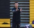 Young coach instructs with hand gestures on indoor court, wearing black sportswear.