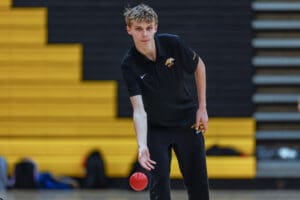 Person in black sportswear playing dodgeball in a gym.