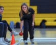 Woman playing bocce ball indoors, aiming with focus amidst a supportive audience.