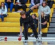Athlete with crutches plays boccia in a gym, showcasing determination and adaptive sports skills.