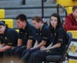 Diverse athletes sitting on a bench during a Special Olympics event, wearing matching team uniforms.