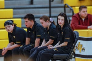 Diverse athletes sitting on a bench during a Special Olympics event, wearing matching team uniforms.