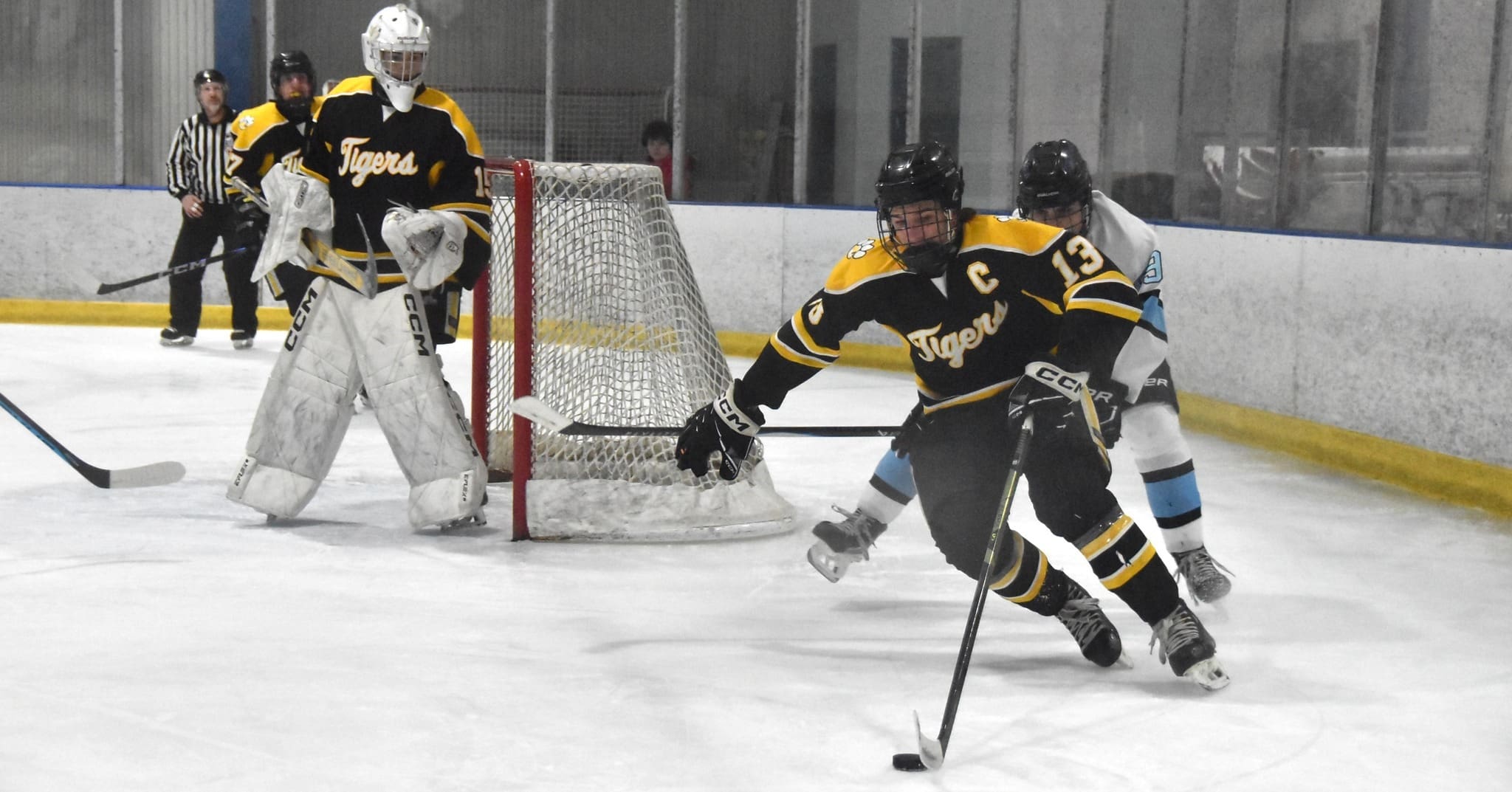 Ice hockey players in action near the goal, wearing black and yellow jerseys.