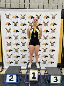 Young athlete wins first place in a sports competition, standing on a podium with a medal.