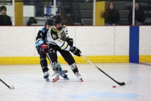 Hockey players in action on the rink, competing for the puck during a roller hockey game.