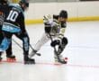 Roller hockey players compete fiercely for the puck on an indoor rink.