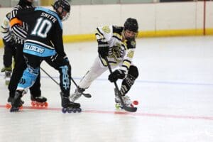 Roller hockey players compete fiercely for the puck on an indoor rink.