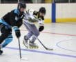 Two roller hockey players competing on the rink in intense action, wearing black and white uniforms.