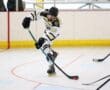 Roller hockey player in action, skating towards puck on indoor rink.
