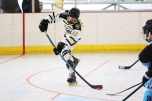 Roller hockey player in action, skating towards puck on indoor rink.