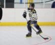 Roller hockey player in action, focused on the puck during an indoor game.