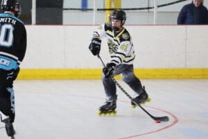 Roller hockey player in action, focused on the puck during an indoor game.