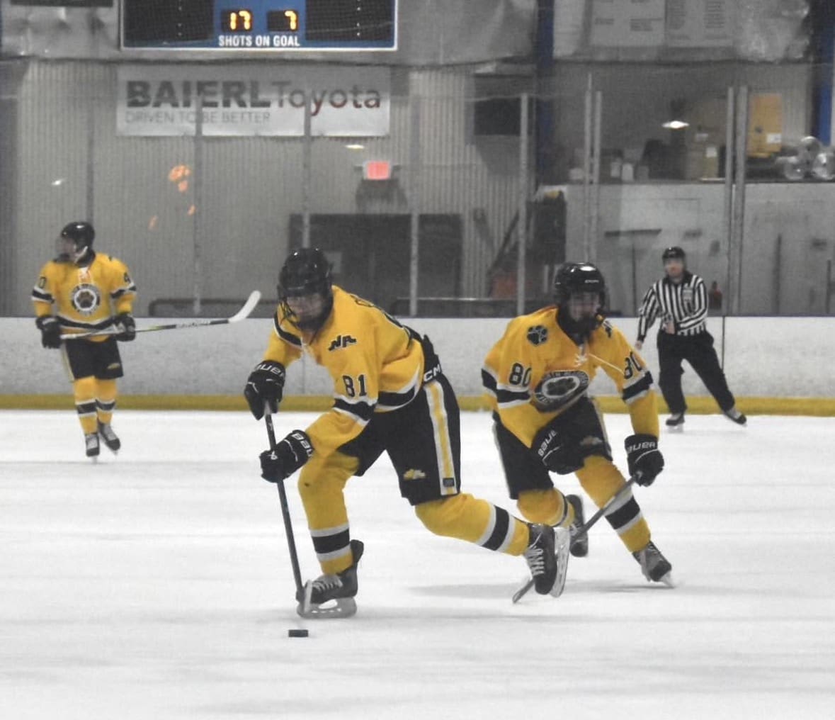 Ice hockey players in yellow jerseys skating on rink during a game.
