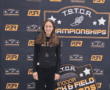 Young athlete at TSTCA Track and Field Championships backdrop, smiling proudly in sportswear.