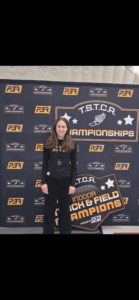 Young athlete at TSTCA Track and Field Championships backdrop, smiling proudly in sportswear.