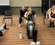 Woman rowing in a competition, supported by a coach, with rowing machine in Lane 14.
