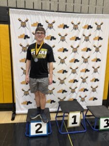 Young athlete stands proudly with a silver medal on a podium at North Allegheny event.