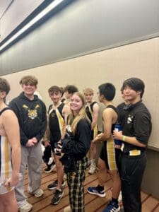 Group of athletes in matching gear, smiling and chatting indoors, preparing for a sports event.