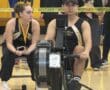 Rowing competition indoor setup with athletes and equipment in a gymnasium.