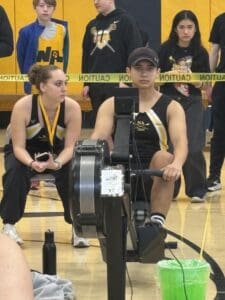 Rowing competition indoor setup with athletes and equipment in a gymnasium.