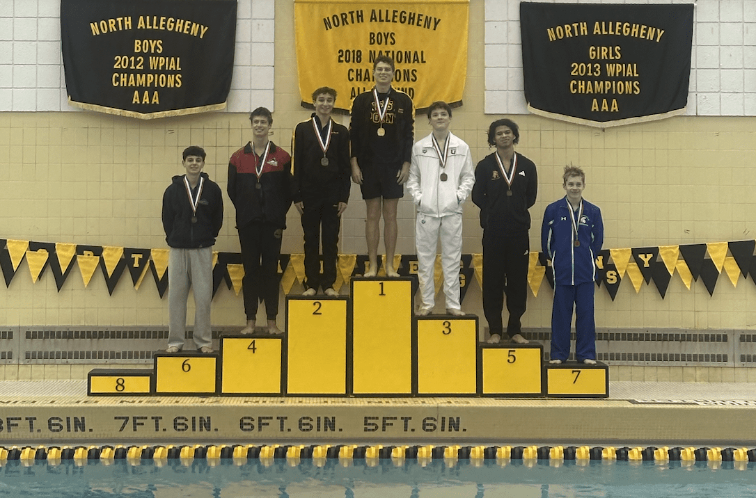 Swimmers on a podium with medals at North Allegheny championship event.