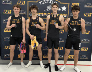 Four athletes from North Allegheny track team pose with medals at TSTCA championships, holding shoes and baton.