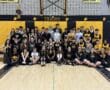 Middle school rowing team group photo in gym, students in matching black and yellow uniforms with medals.