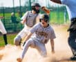 Baseball player sliding into home plate, celebrating while umpire calls the play during a thrilling game moment.