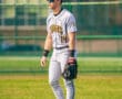 Baseball player in gray Tigers uniform stands on field, ready for action, with glove in hand and sunglasses on.