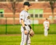 Player in gray baseball uniform stands on the field, ready for play during a sunny game day.